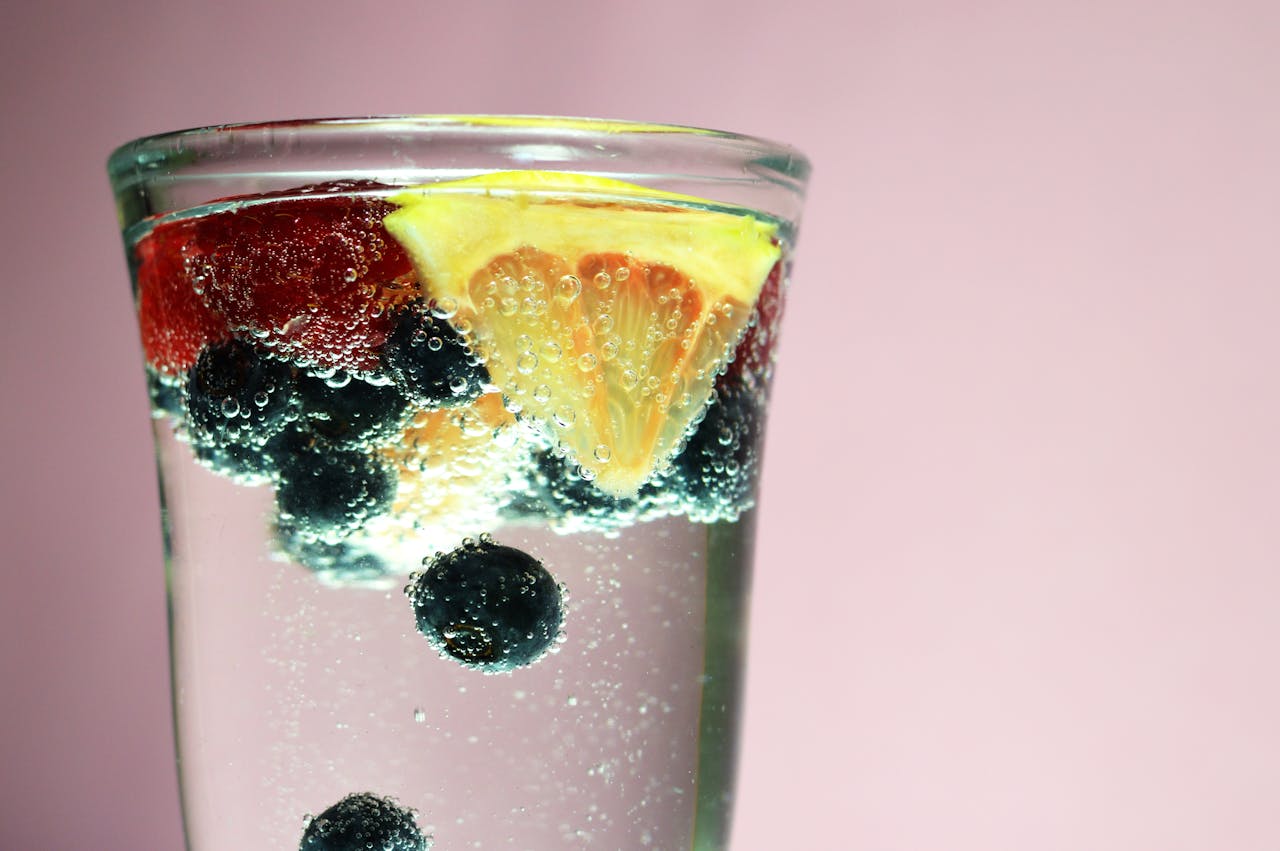 Glass of sparkling water with citrus and berries, refreshing and invigorating.